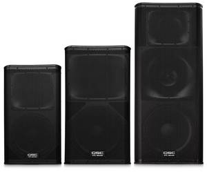 Three black QSC speaker KW Series speakers of varying sizes lined up next to each other.