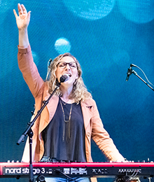 Image of woman on stage with her hand up